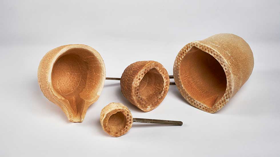 A collection of four different sized vacuum-formed refractory test ladles rest on a white background.